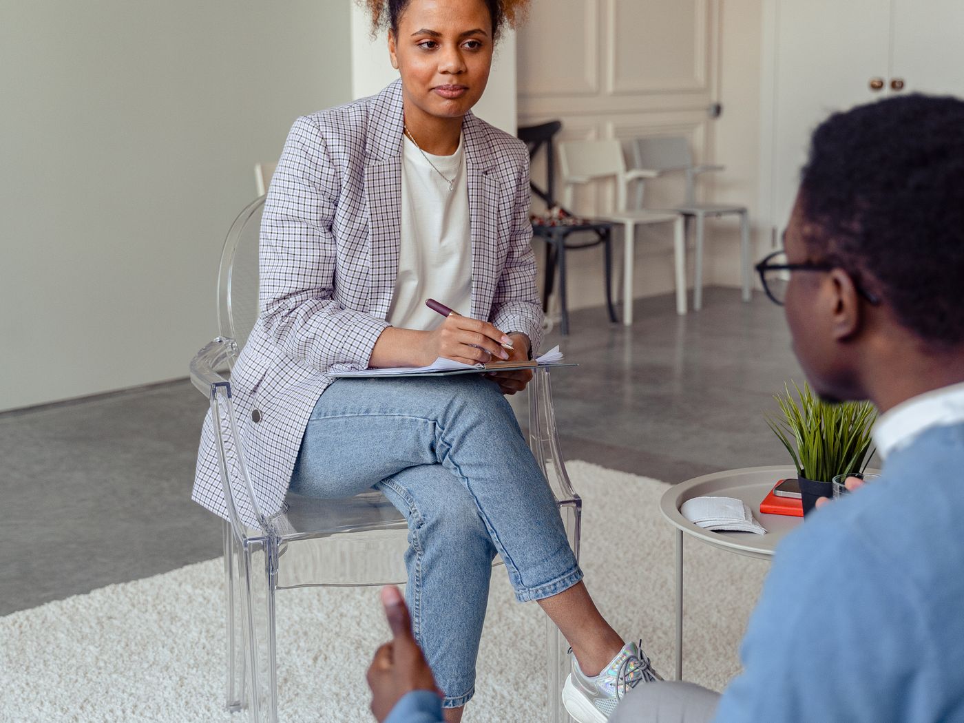 A mental-health clinician listens attentively to a young adult client during an outpatient therapy session.